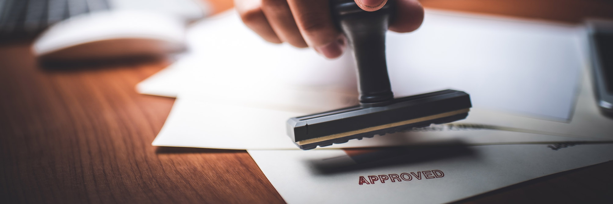 Close-up Of A Person’s Hand Stamping With Approved Stamp On Text Approved Document At Desk,  Contract Form Paper